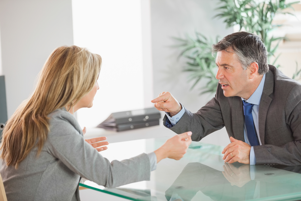 A blonde businesswoman and a mature businessman having an argument in an office